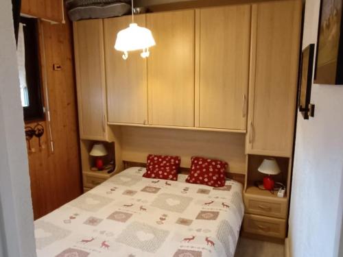 a small bedroom with a bed and two red pillows at Appartement cosy proche pistes ski avec garage - FR-1-498-112 in Thollon