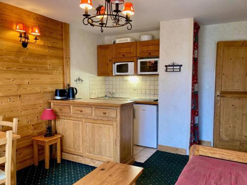 une petite cuisine avec des placards en bois et une table dans l'établissement Studio cosy au pied des pistes avec balcon et animaux admis - FR-1-811-19, à Les Deux Alpes