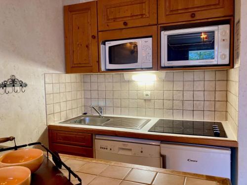 une cuisine avec un évier et un micro-ondes dans l'établissement Studio cosy au pied des pistes avec balcon et animaux admis - FR-1-811-19, à Les Deux Alpes