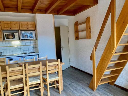 une cuisine et une salle à manger avec une table et un escalier dans l'établissement Duplex cosy sous les toits, pied des pistes, animaux admis - FR-1-811-21, à Les Deux Alpes
