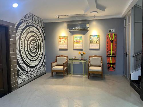 a room with two chairs and a wall with a painting at Hotel Sabana del Sinu By GEH Suites in Montería