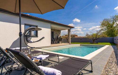 a pool with chairs and an umbrella next to a house at Gorgeous Home In Jursici With Wifi in Juršići