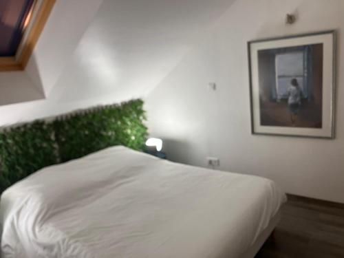 - une chambre dotée d'un lit blanc avec une photo sur le mur dans l'établissement Duplex coloré et lumineux, à Provins