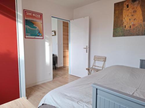 une chambre avec un lit blanc et une chaise dans l'établissement Maison St Marc proche plage, 3chambres, à Saint-Nazaire