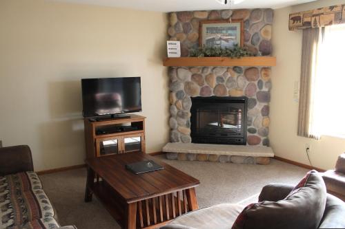 Una sala de estar con televisión y chimenea. en 2 Bedroom Condo Duck Lake, en Eagle River