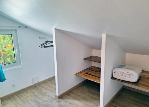 a room with white walls and a staircase with wooden shelves at Studio cosy avec vue sur mer à Saint-Leu, 31 m² in Saint-Leu