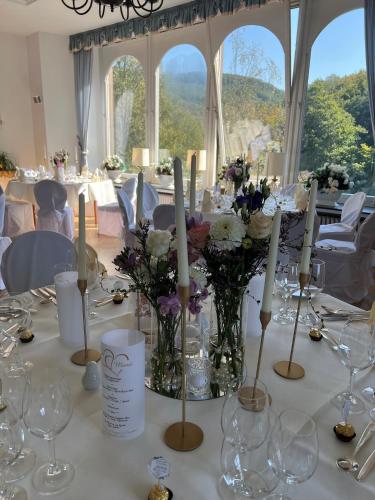 a table with flowers and candles in a room with windows at Hotel und Restaurant Burg Schnellenberg in Attendorn