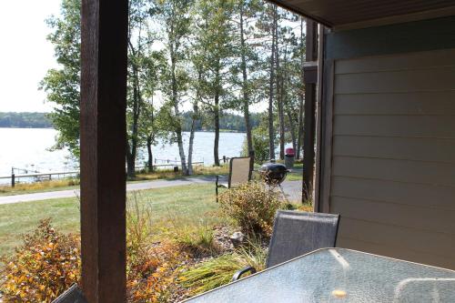 une terrasse couverte avec une table et des chaises et une vue sur l'eau dans l'établissement Duck Lake two Bedroom Condo at Wild Eagle Lodge, 111, à Eagle River