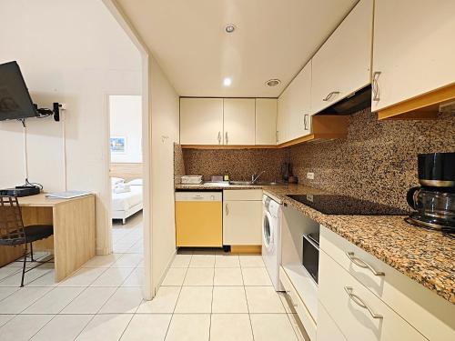 une cuisine avec des placards blancs et un bureau. dans l'établissement Viva Riviera Residence Marina Croisette, à Cannes