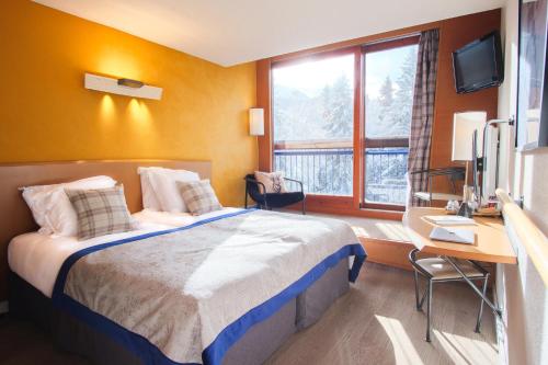 a bedroom with a bed and a desk and a television at Belambra Clubs Arc 1800 - Hôtel Du Golf in Arc 1800