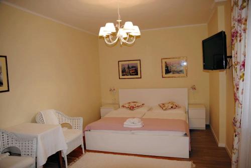 a bedroom with a bed and a television and a chandelier at Penzion 77 - Garni in Pezinok
