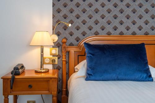 - un lit avec un oreiller bleu et une lampe sur une table dans l'établissement Sun Riviera Hotel, à Cannes