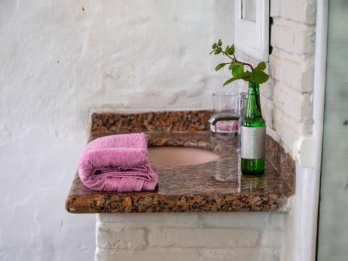 a bathroom sink with a pink towel and a bottle at Pousada Gendra's in Imbituba