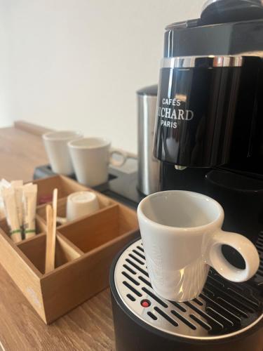 a coffee maker with a coffee cup on a table at Aka Lodge Lyon Eurexpo Arena Stadium in Meyzieu