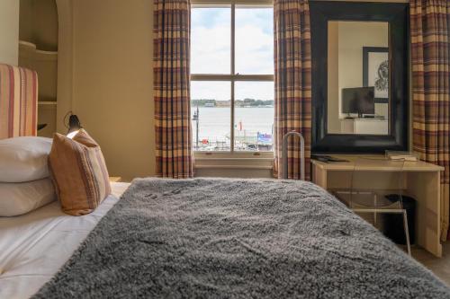 a bedroom with a bed and a large window at The Pier Hotel in Harwich