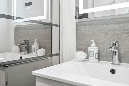 une salle de bain blanche avec un lavabo et un miroir dans l'établissement L'Atelier Secret - Batignolles - Métro - Paris 17, à Paris