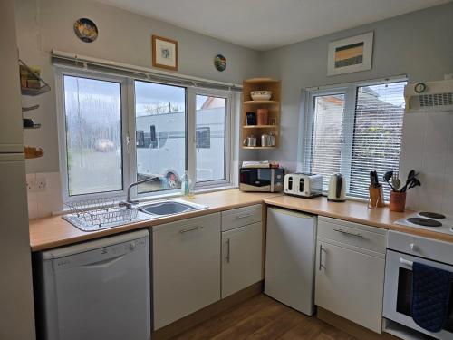 a kitchen with a counter with a sink and two windows at Ty Pren Bach in Maenclochog