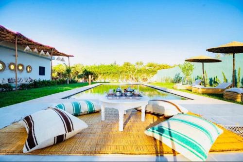 a white table and chairs next to a swimming pool at RIAD DAR ESSOURY Marrakech in NʼChaba