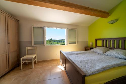 une chambre avec un lit, une fenêtre et une chaise dans l'établissement Résidence Au Brin d'Olivier, à Saint-Martin-dʼArdèche