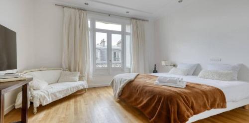 - une chambre blanche avec un grand lit et un canapé dans l'établissement Renovated, Amazing & Huge Flat of 200 sqm Paris 16, à Paris