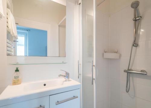 une salle de bain blanche avec un lavabo et une douche dans l'établissement Appartement Saint-Malo - Vue mer, à Saint-Malo