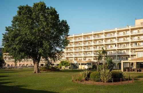 a large white building with a tree in front of it at Mitsis Messonghi in Moraitika