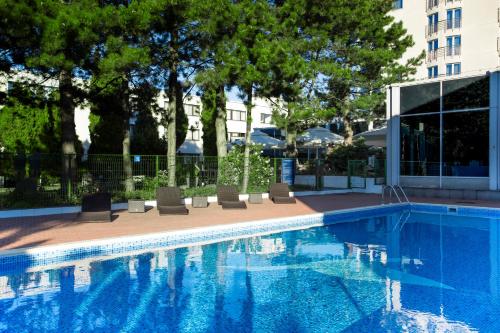 a swimming pool with chairs and a building at Novotel Warszawa Airport in Warsaw