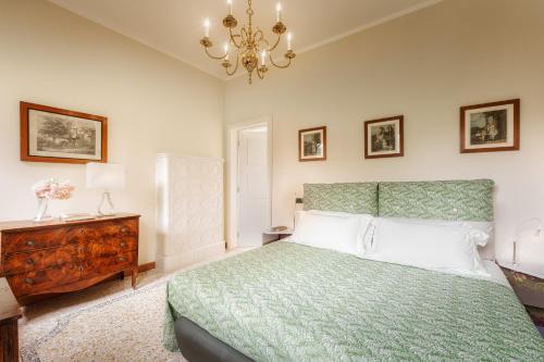 a bedroom with a green bed and a chandelier at Villa La Pioppa in Pieve dʼOlmi