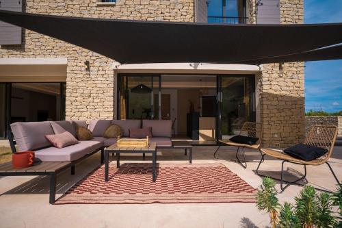 a patio with a couch and a table and chairs at Stone villa with heated pool in Gordes in Gordes