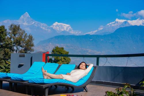 a woman laying in a hammock on a patio with mountains at Himalayan Front Hotel by KGH Group in Pokhara