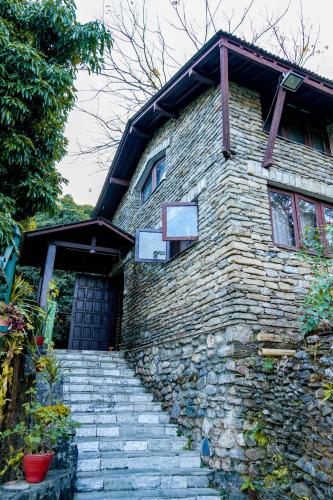 a stone house with stairs leading up to a door at Himalayan Front Hotel by KGH Group in Pokhara