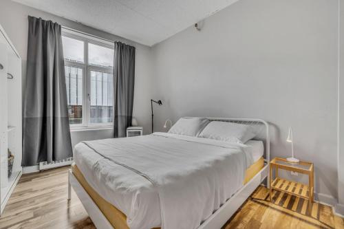 a white bedroom with a large bed and a window at Initial 303 Québec in Quebec City