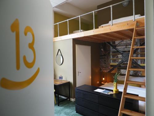 a room with a bunk bed with a desk and a staircase at Hostel Roots in Tilburg