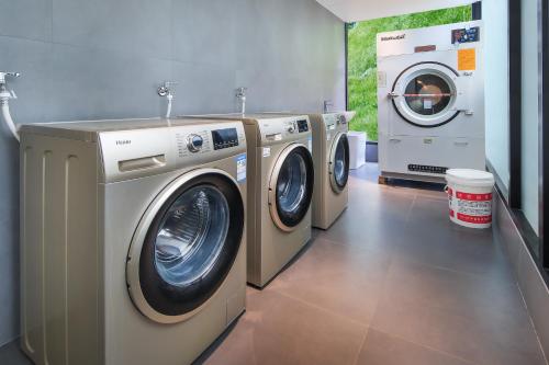 two washing machines and a dryer in a laundry room at Longji Skyreach Peak Resort - Golden Buddha Summit in Longsheng