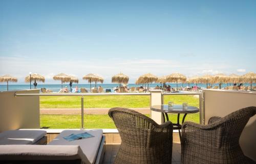 a patio with chairs and tables and a view of the beach at Mitsis Messonghi in Moraitika