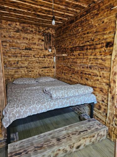 a bed in a room with a wooden wall at Ribnjak Filopivic in Pleš
