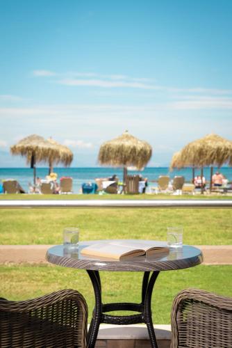 a table with an open book on it next to a beach at Mitsis Messonghi in Moraitika