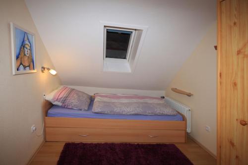 a small bed in a small room with a window at Ferienwohnung 'auf dem Burstel' in Kleines Wiesental