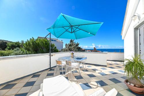 a patio with a table and a blue umbrella at Apartments Marić in Primošten