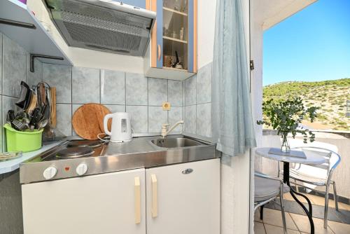 a small kitchen with a sink and a balcony at Apartments Marić in Primošten