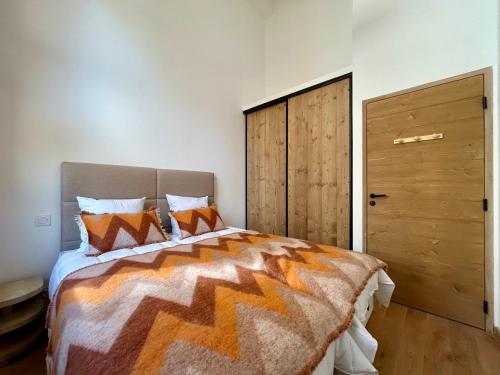 une chambre avec un grand lit avec des oreillers orange dans l'établissement Homency - Residence L'Expression A22, à L'Alpe-d'Huez
