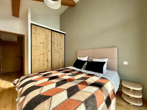 une chambre avec un grand lit avec une couverture à carreaux dans l'établissement Homency - Residence L'Expression A22, à L'Alpe-d'Huez