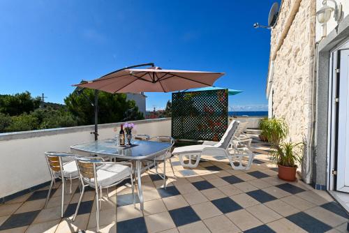 a patio with a table and chairs and an umbrella at Apartments Marić in Primošten