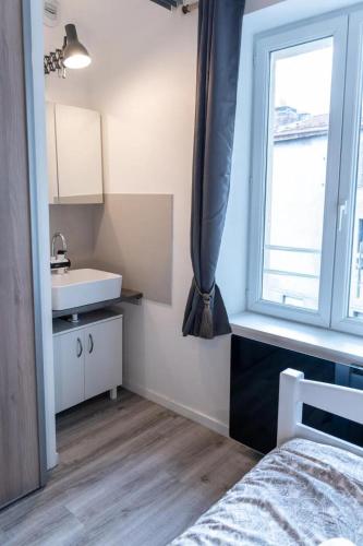 une chambre avec un lit, un lavabo et une fenêtre dans l'établissement La STÉPHANOISE, à Saint-Étienne