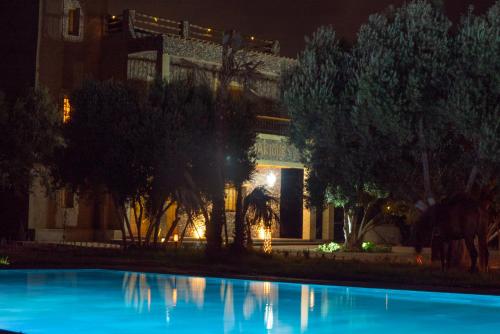 a building with a swimming pool at night at Riad AL MAKTOUB maison d'hotes écologique in Marrakech