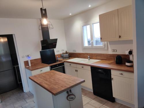 une cuisine avec des armoires blanches et un réfrigérateur noir dans l'établissement Villa Caroux, à Bédarieux