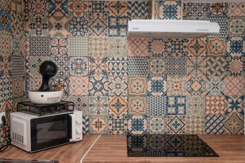 a kitchen with a microwave and tiles on the wall at AL-Bash in Elvas