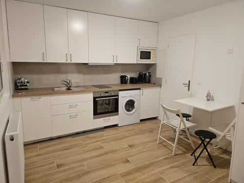 a kitchen with white cabinets and a table and chairs at L'harmonie d'Eden Harmony of Eden in Sainte-Geneviève-des-Bois