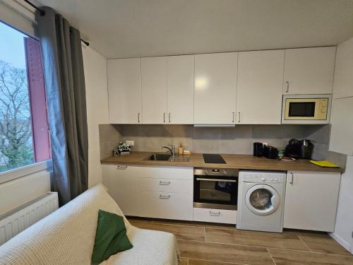 a kitchen with white cabinets and a washing machine at L'harmonie d'Eden Harmony of Eden in Sainte-Geneviève-des-Bois