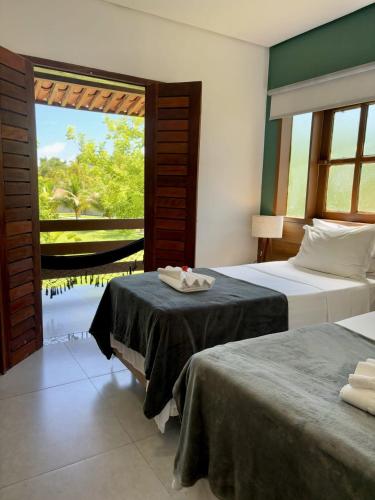 a bedroom with two beds and a view of the water at Angá Beach Hotel in São Miguel dos Milagres